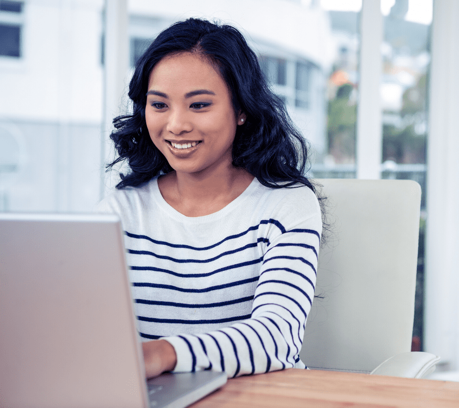 Asian woman looking at laptop smiling