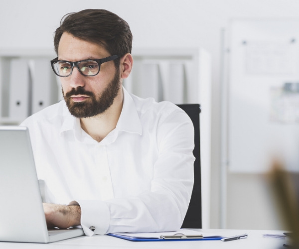 serious man with glasses at laptop