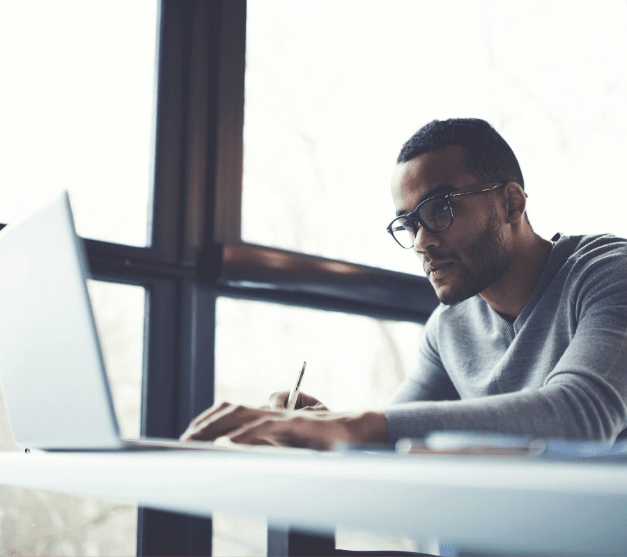 man with glasses studying laptop