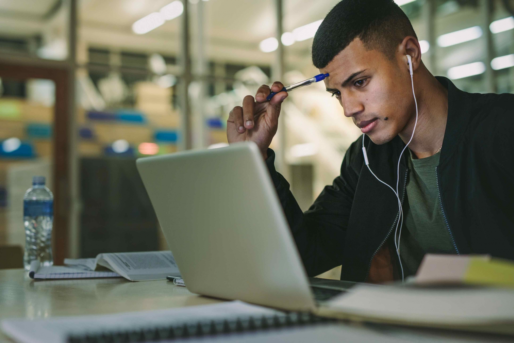 male studying at computer with pencil