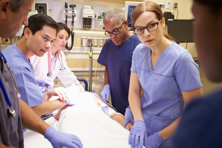 er team in training standing over hospital bed